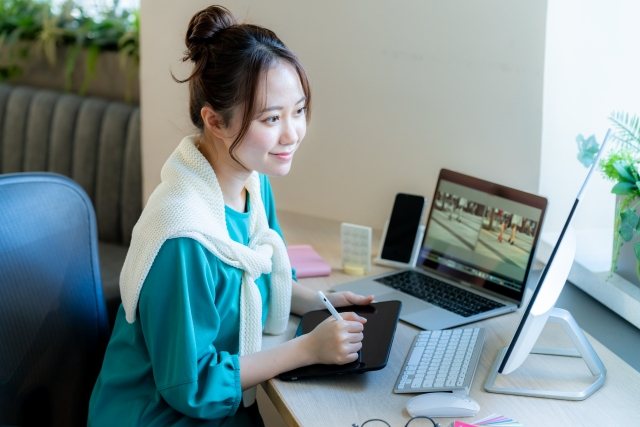 ペンタブレットとパソコンで制作している女性