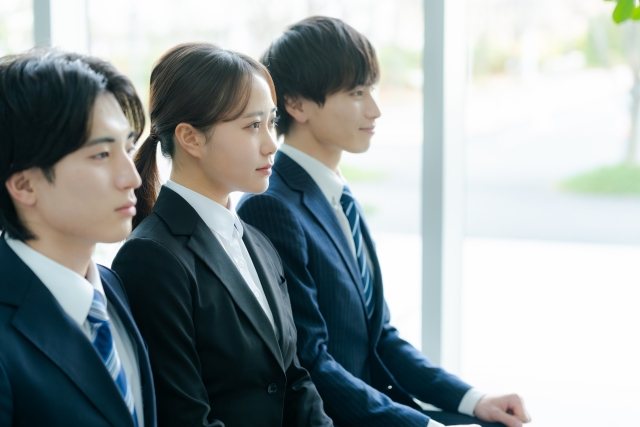 窓辺に並んで座るリクルートスーツ姿の3人